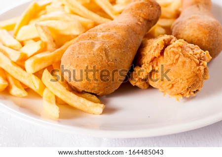 Fried chicken legs and french fries on the plate.Selective focus on the front chicken leg