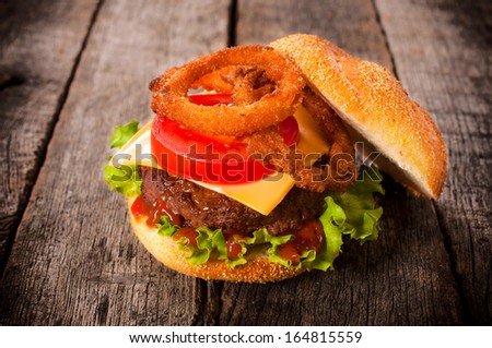Single hamburger with onion rings on the wooden table