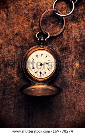 Old pocket watch on the wooden background from above