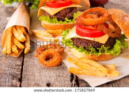 Onion rings,french fries and cheeseburger on the wooden table