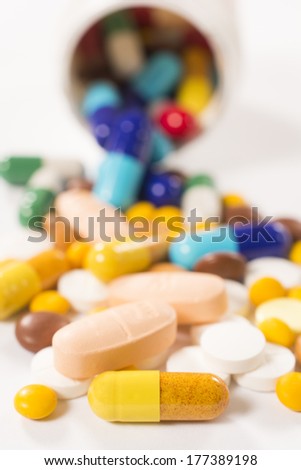 Bunch of pills on white background.Selective focus on the front yellow pill