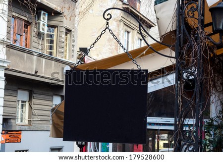 Old, black and wooden blank billboard on the chains, with space for your own copy.