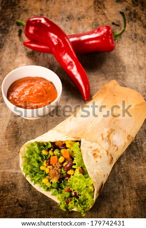 Sandwich wrap and salsa sauce on a wooden table. Selective focus in the middle of sandwich.