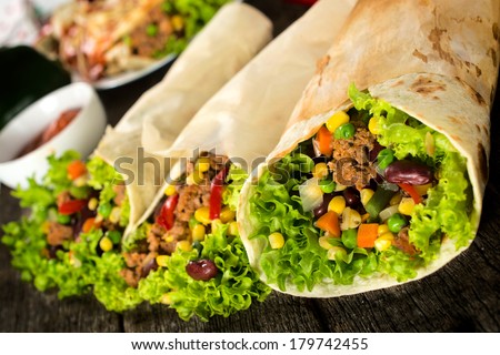 Beef and vegetables in tortilla wrap sandwiches. Selective focus on the front sandwich.