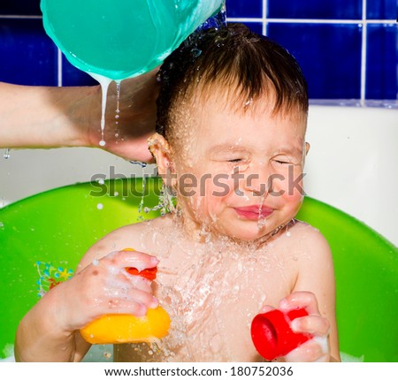 Mother splashing water on the child head during bath time