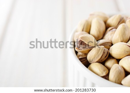 Heap of pistachio in the cup and blank space on left side for text.Selective focus on pistachio on the left