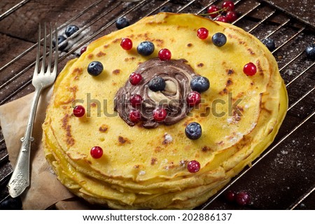 Sweet homemade pancakes with berry fruit and chocolate cream.Selective focus on the top of pancakes