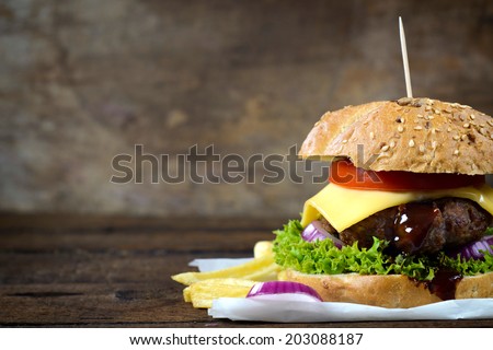 Juicy cheeseburger on the wooden background