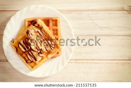 Tasty waffles with bananas and melted chocolate