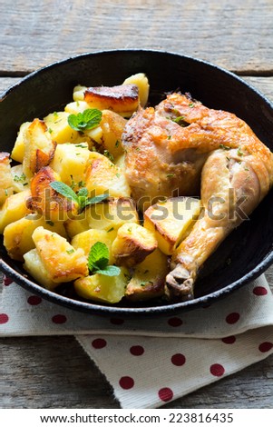 Prepared potato and chicken leg in the pan.Selective focus in the middle of pan