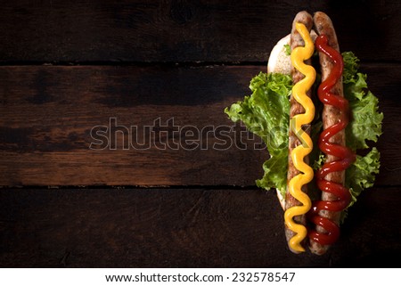 Smoked and grilled sausages with mustard and ketchup on wooden background.Blank space on the left side