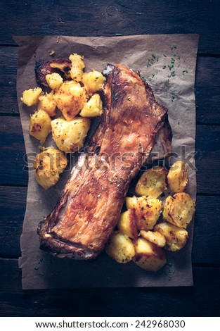 Lamb ribs with baked potatoes from above on wooden background