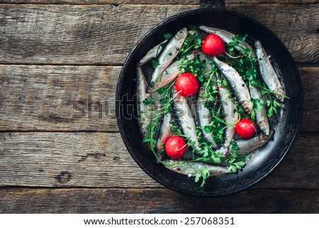 Smelt fishes in old pan on wooden background with blank space