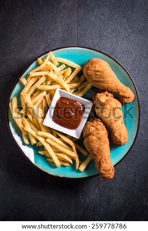 Fried chicken legs and French fries with bbq sauce in the plate from above