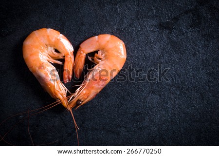 Boiled tiger shrimps heart shape on table with blank space on the right side