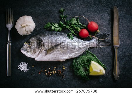Raw glithead fish with ingredients from above on dark background
