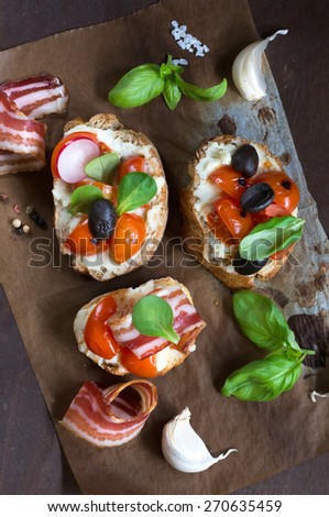 Bruschettas with bacon and tomato on wooden background from above,selective focus