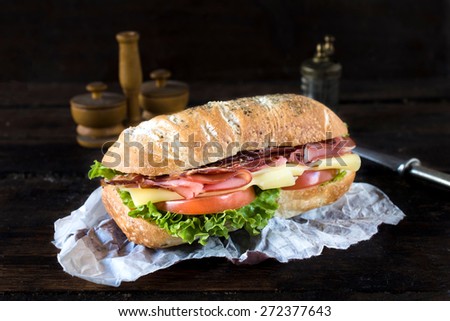 Ciabatta bread stuffed with cheese,meat and vegetables on wooden background,selective focus