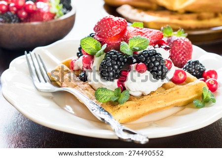 Tasty baked waffles with vanilla cream and berry fruits in the plate,selective focus