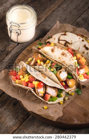 Tortilla wrap sandwiches with fried chicken and vegetables on wooden background,selective focus