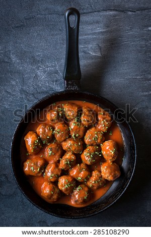 Meatballs with tomato sauce in the pan on dark background from above