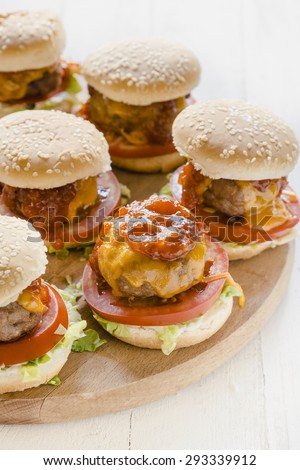 Mini beef burgers with melted cheddar cheese and bbq sauce on wooden board,selective focus