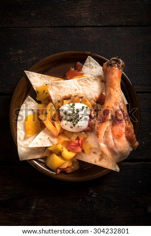 Chicken drumstick and tortilla bread in the plate,from above on wooden background