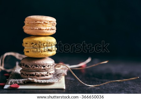 Sweet and colorful macaroon cookies tower on dark background with blank space,selective focus