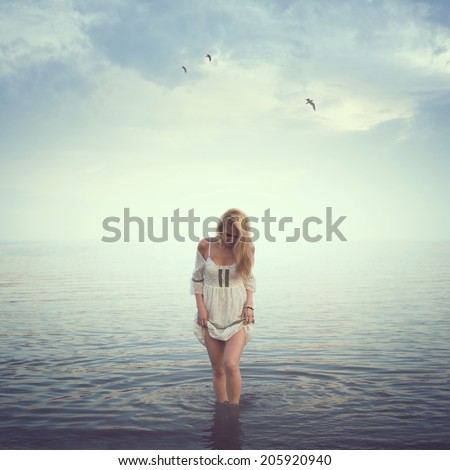 Beautiful girl in the water. Beach, sunrise, cold morning. concept loneliness love sadness romance