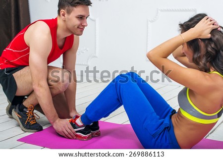 Man helping a woman or girl in making abdominal crunch,  exercises concept training exercising workout fitness aerobic.