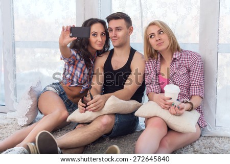 two girls and guy friends taking selfie together wearing summer clothes  jeans shorts jeanswear street urban casual style having fun at home.