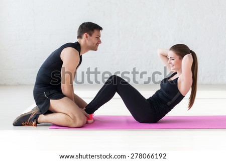woman doing abdominal crunches press exercise on the mat with her sports male trainer in gym concept sport, fitness, lifestyle and people.