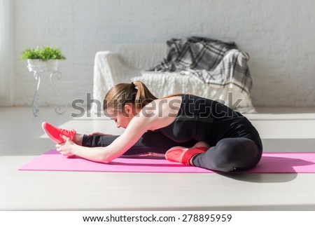 Fit woman high body flexibility stretching her leg and back to warm up doing aerobics gymnastics exercises at home.