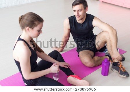 Sport connecting people friends relaxing after workout girl drinking water. Young couple in sports clothing sitting talking conversing