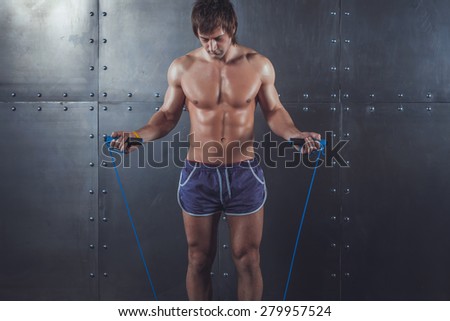 Fitness model muscular man with skipping jumping rope around his neck with copy space healthy lifestyle bodybuilding concept.