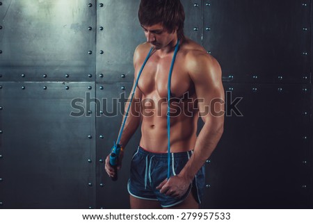 Fitness model muscular man with skipping jumping rope around his neck with copy space healthy lifestyle bodybuilding concept.