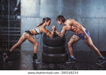 Athlete muscular sportsmen man and woman with hands clasped arm wrestling challenge between a young couple Crossfit fitness sport training lifestyle bodybuilding concept