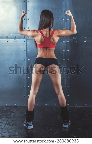 Muscular active athletic young woman showing muscles of the back shoulders and hands fitness, sport, training and lifestyle concept