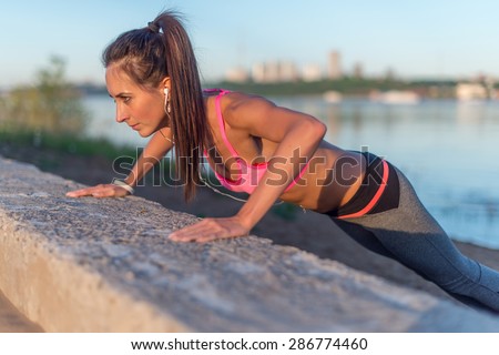 Fitness woman doing push ups Outdoor training workout summer evening side view Concept sport healthy lifestyle
