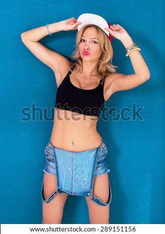 Young blonde girl posing wearing urban clothes sports bra swag baseball cap or hat.