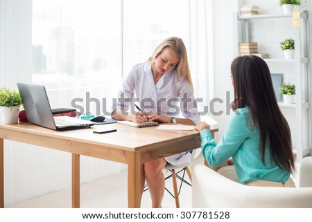 Doctor talking to patient in office, taking notes