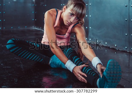 Fit woman doing stretching exercises her muscles back and legs before a training warm up at gym concept fitness, sport, lifestyle