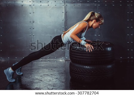 Sportswoman. Fit sporty athlete woman doing push ups on tire strength power training concept crossfit fitness workout sport and lifestyle side view.