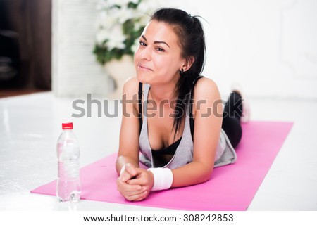 Young woman relaxing after workout at home lying on yoga mat concept healthy lifestyle, training, diet.