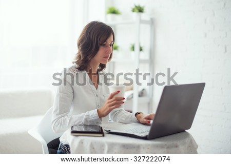 young business woman working at desk typing on a laptop in office and drinking coffee.