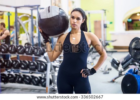 Muscular fit woman workout in gym. Strong female doing exercise with medicine ball in fitness club