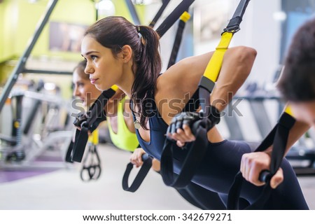 Women doing push ups training arms with trx fitness straps in the gym Concept workout healthy lifestyle sport