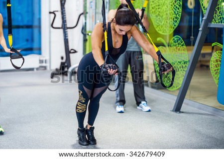 Young woman training exercise push ups with trx fitness straps in the gym  Concept sport workout healthy lifestyle.