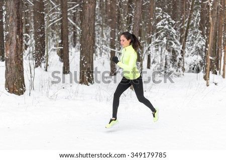 young fit athlete woman running at forest Sprinting during winter training outside in cold snow weather