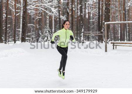 Athlete woman runner running in winter park or forest